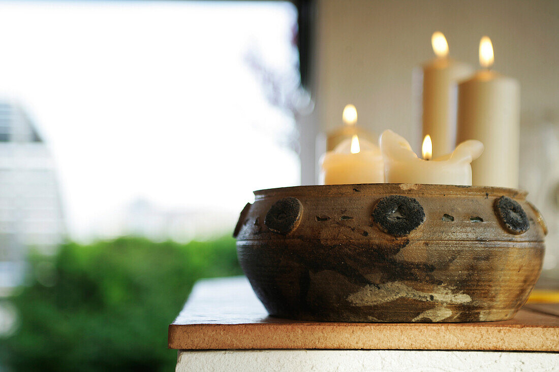 Lighted candles in a brown bowl