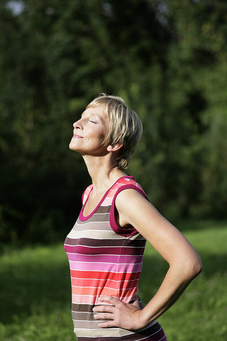 Ältere Frau steht in der Sonne