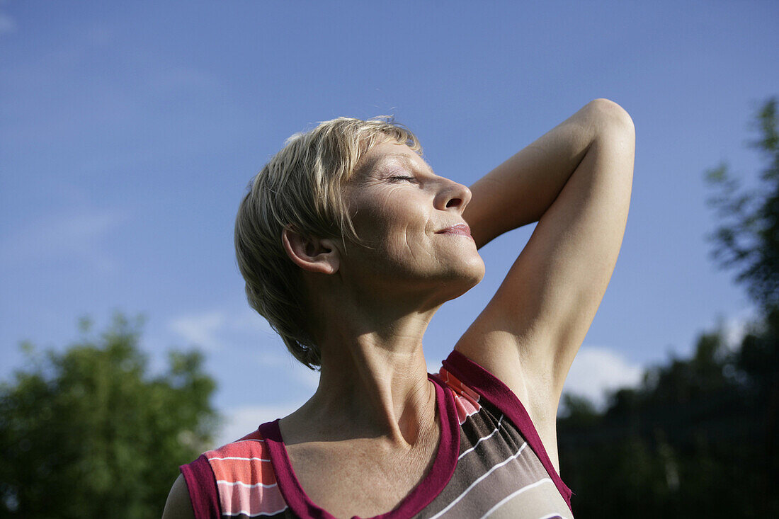 Mature woman stretching in sun, Styria, Austria