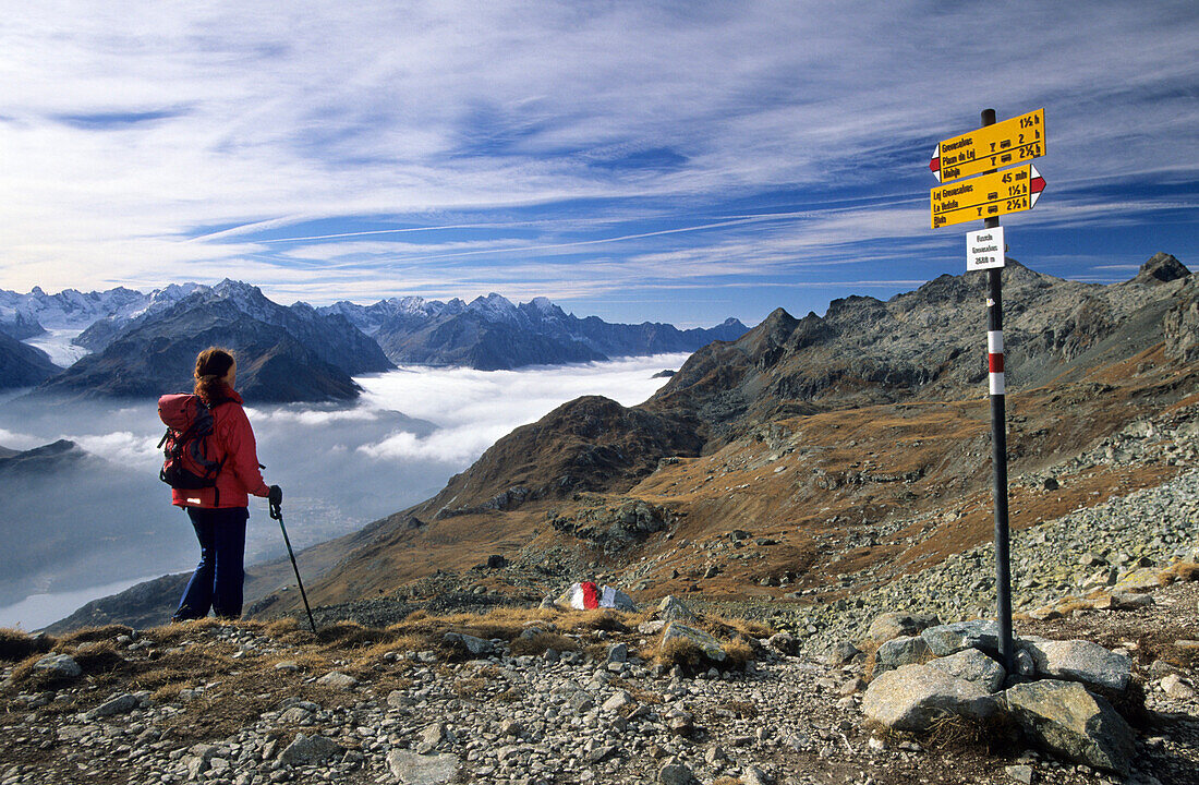 Junge Frau in der Fuorcla Grevasalvas mit Blick auf das Nebelmeer über dem Malojapass, Oberengadin, Engadin, Graubünden, Schweiz