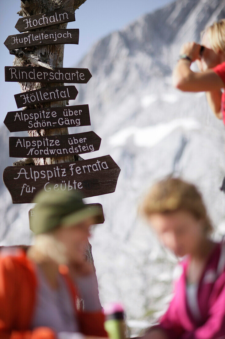 Two young women near sign post, Werdenfelser Land, Bavaria, Germany