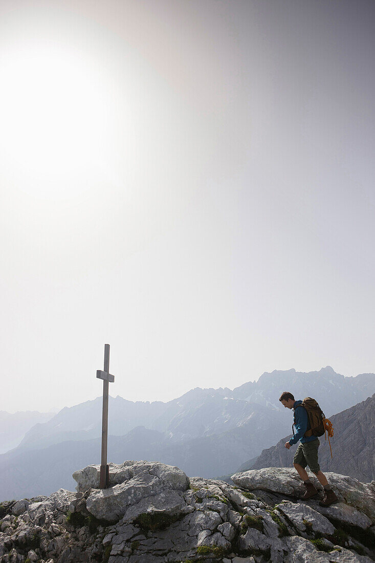 Hiker arriving summit cross, Werdenfelser Land, Bavaria, Germany