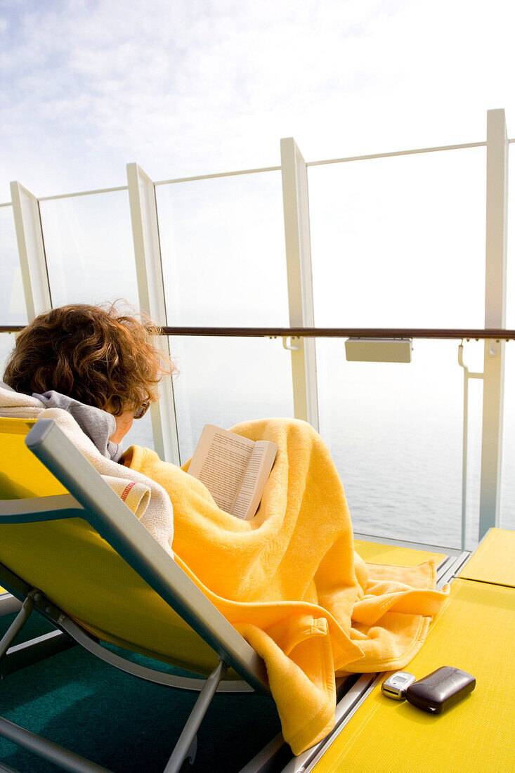 Eine Frau liest auf dem Deck des Kreuzfahrtschiffs Aidadiva