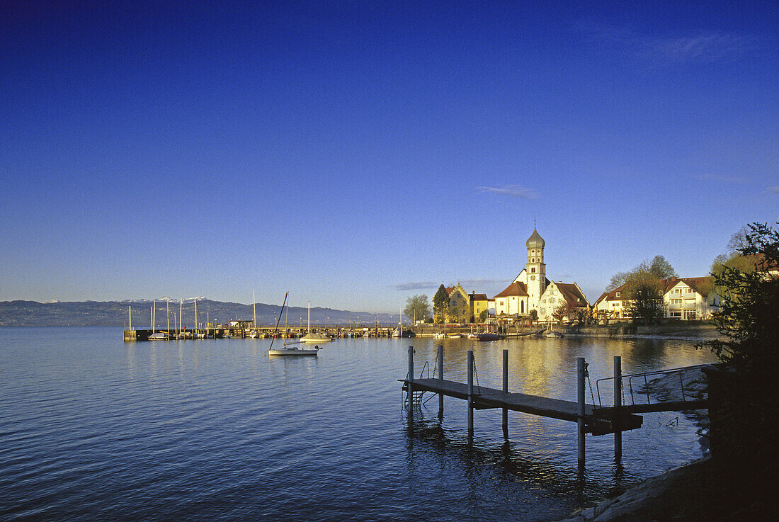 Church and castle at the lakeshore under blue sky, Wasserburg, Lake Constance, Bavaria, Germany