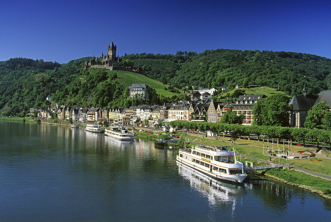Reichsburg unter blauem Himmel und Ausflugsschiffe am Ufer, Mosel, Rheinland-Pfalz, Deutschland