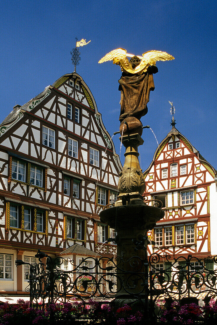 Brunnen mit Skulptur und Fachwerkhäuser unter blauem Himmel, Bernkastel-Kues, Rheinland-Pfalz, Deutschland