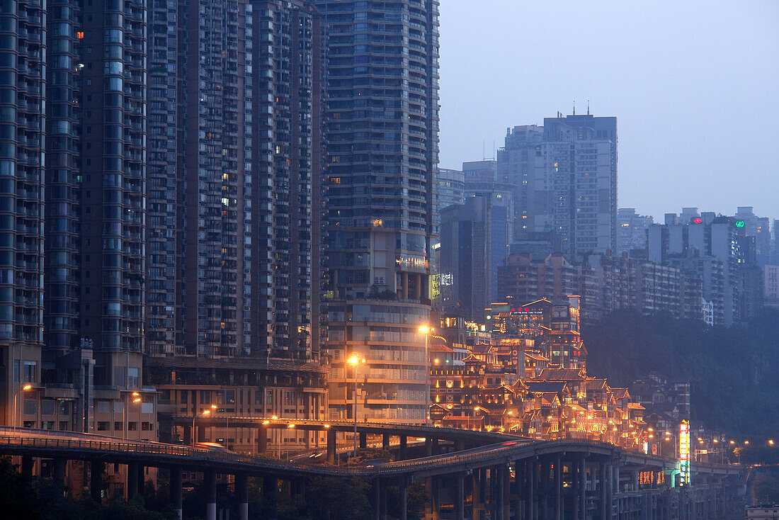 Dunkle, futuristische aussehende Wolkenkratzer und die hellerleuchtete Hongyadong Folklore Mall, Chongqing, China, Asien