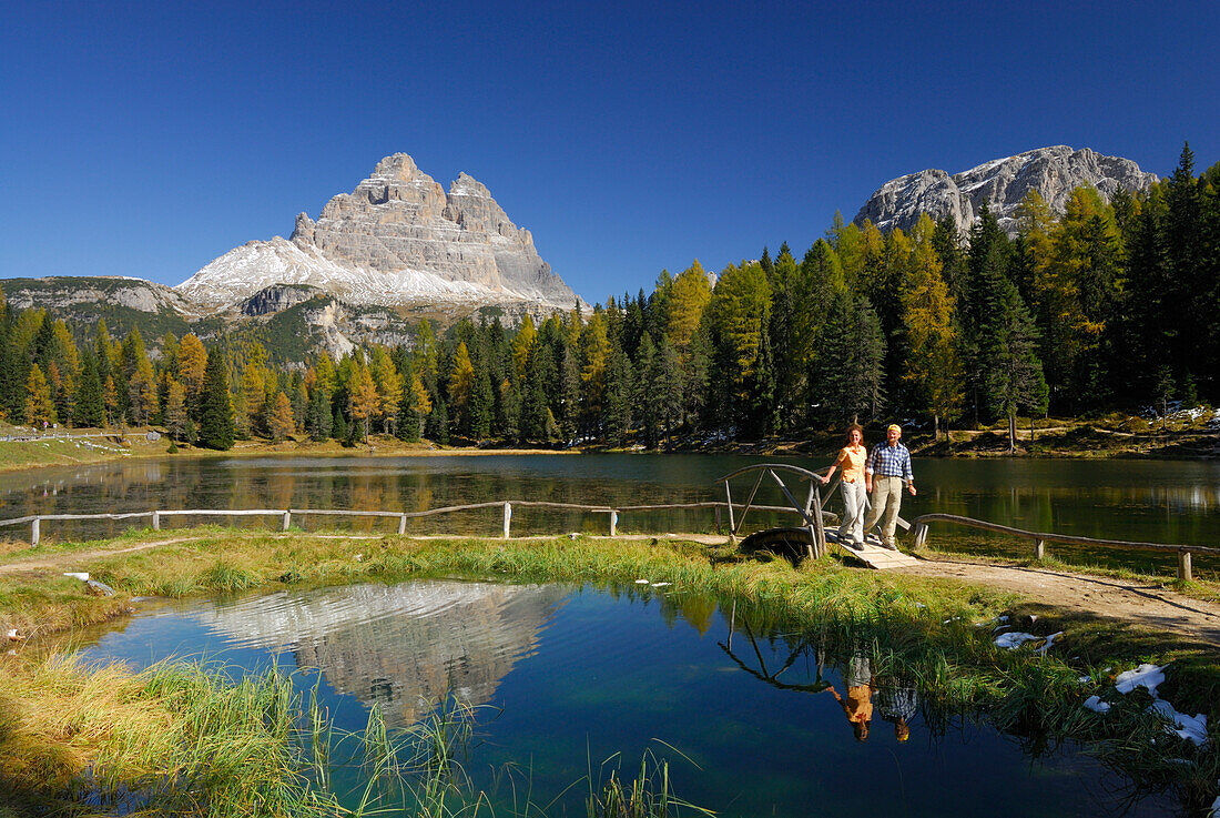 Drei Zinnen über dem Antornosee mit Paar auf Weg mit Brücke, Dolomiten, Südtirol, Italien