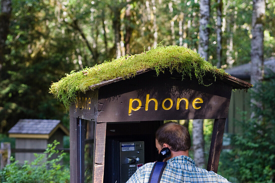 Ein Mann an moosbedecktem Telefonhäuschen im Olympic Nationalpark, Washington, USA