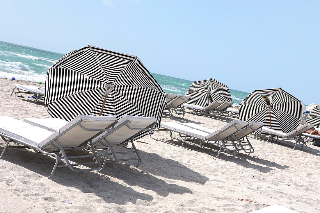 Sonnenliegen und Sonnenschirme am Strand in der Sonne, South Beach, Miami Beach, Florida, USA
