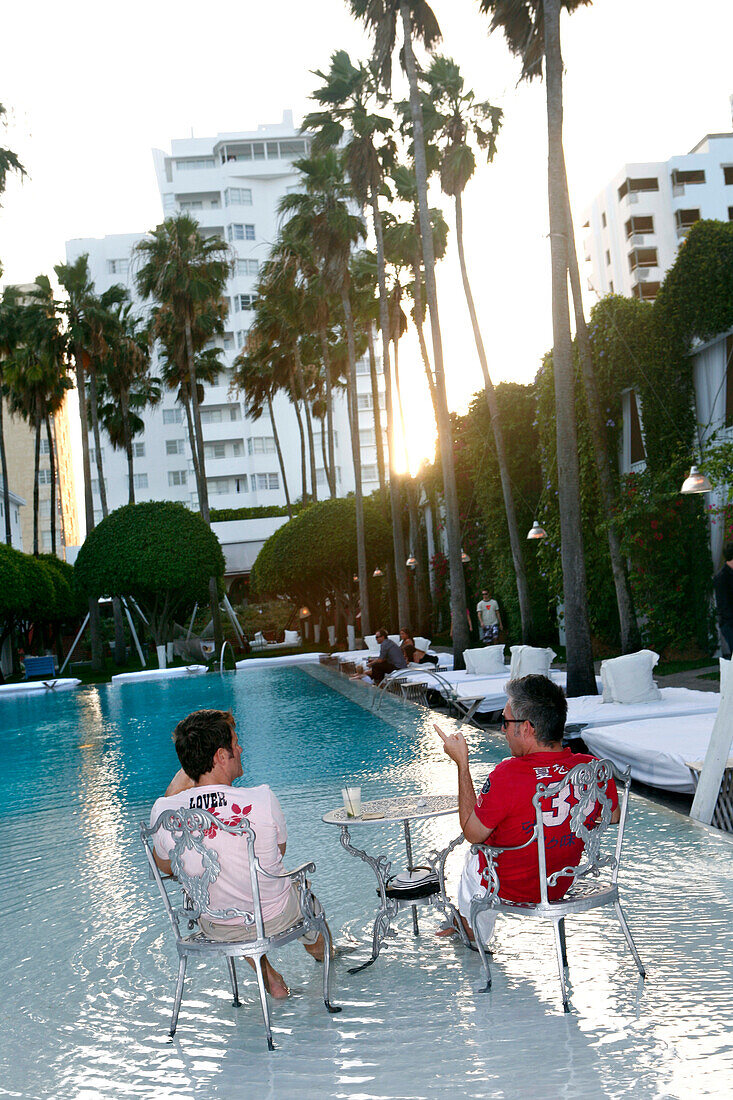Zwei Männer entspannen sich im Pool des Delano Hoterl Bei Sonnenuntergang, South Beach, Miami Beach, Florida, USA