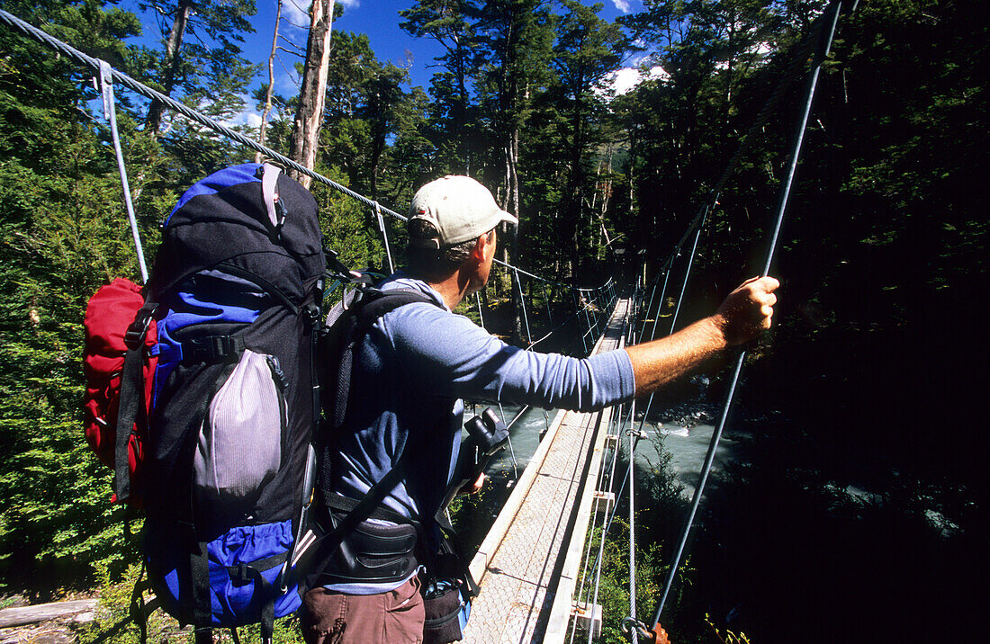 Man on a suspension bridge above the Rees Dart River, Mount Aspiring National Park, South Island, New Zealand, Oceania