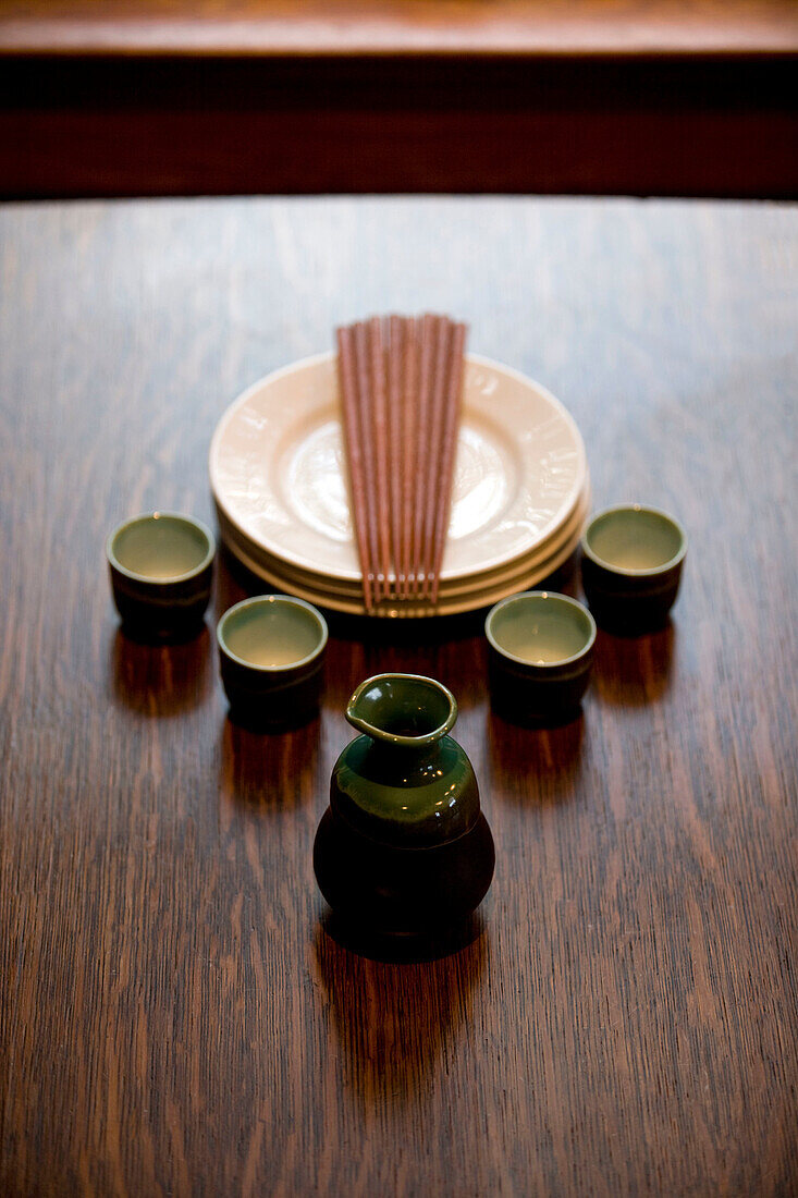 Porcelain sake pitcher and tumblers on oak table