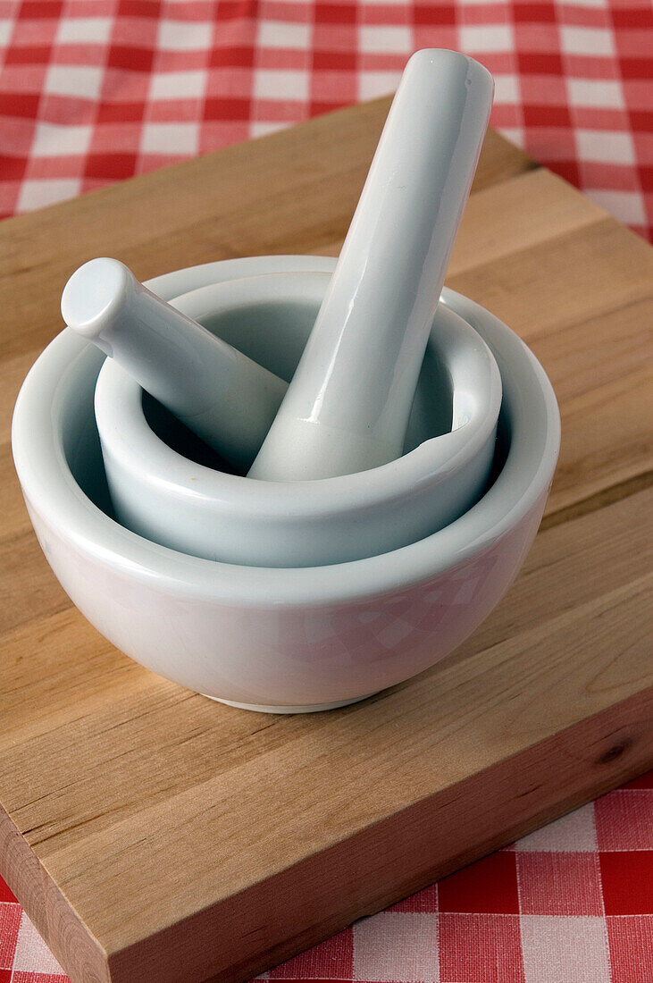 2 mortars and pestles on cutting board, on red checkered table cloth