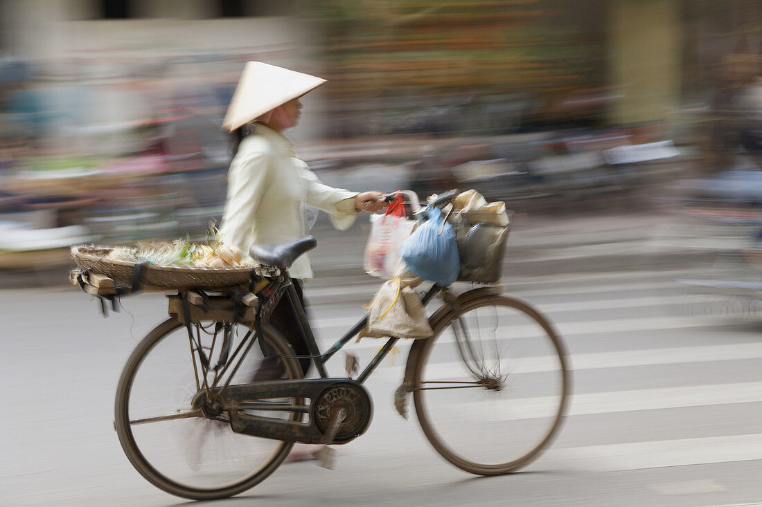 Woman street vendor pushing a bicycle, Hanoi, Vietnam