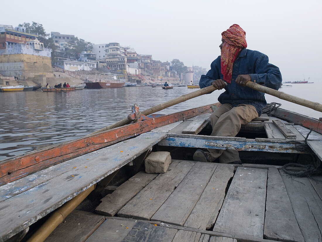 A boat man rows his boat to show visitors life along the holy river Ganges, an important pilgrimge site for Hindu's, in Varanasi, Uttar Pradesh, India