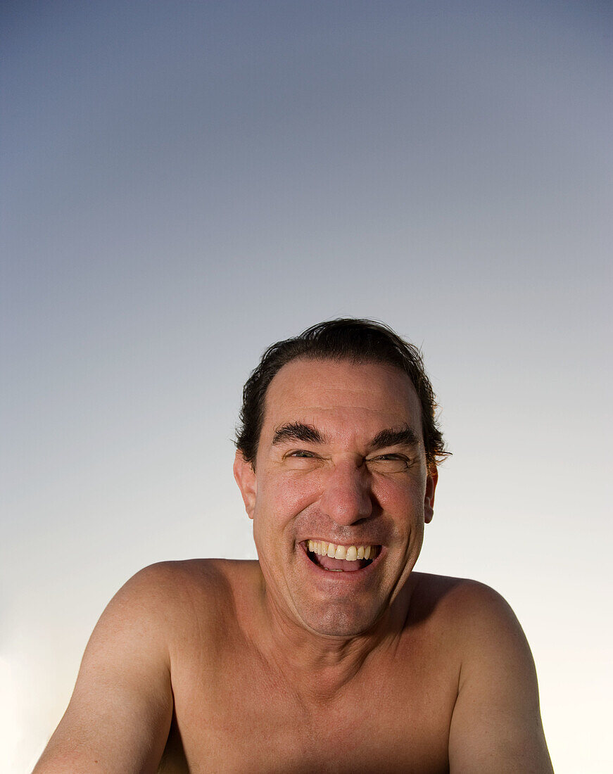 Man with no shirt looking at camera laughing outdoors, Hollywood, Florida, USA