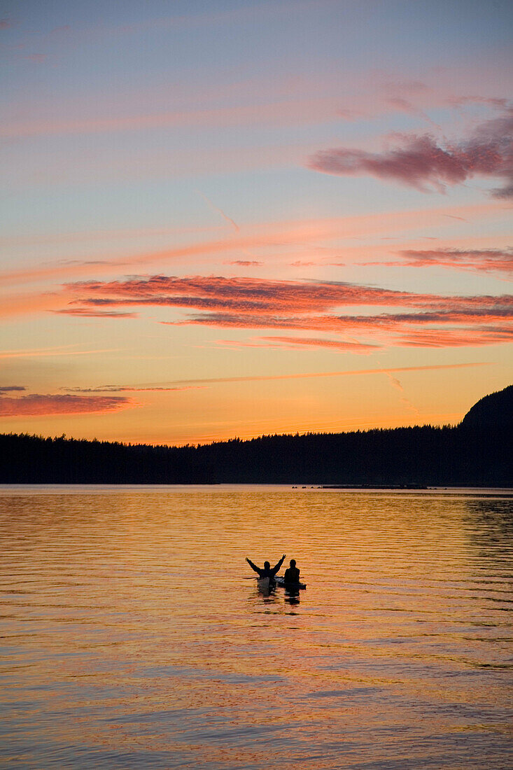 Kayakers enjoying a sunset on the water in simlik bay. Washington.  NW USA