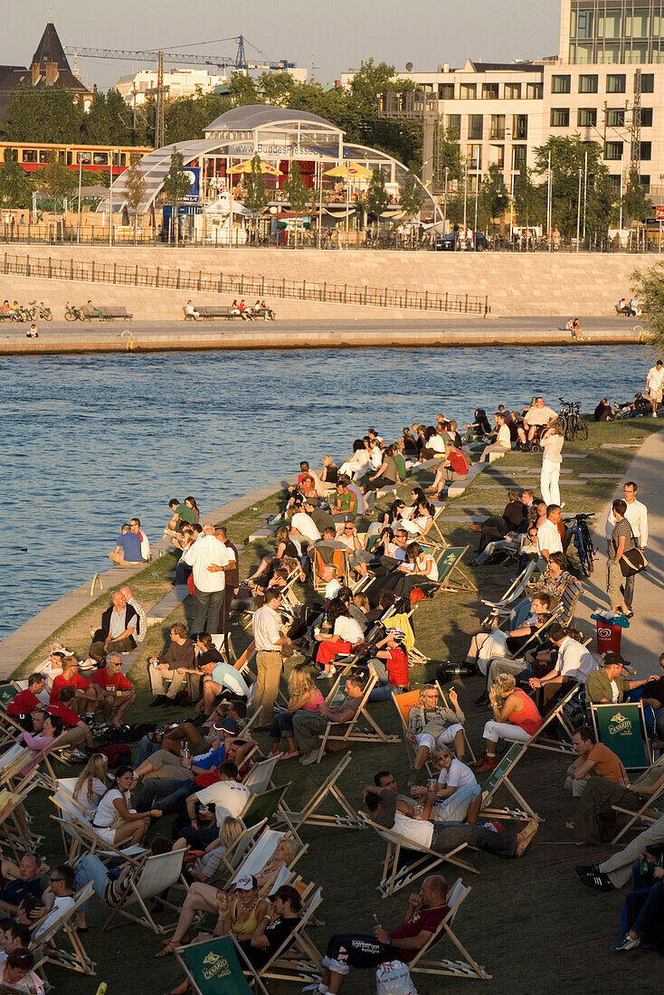 People sitting on deck chairs at the bank of the river Spree in the sunlight, Berlin, Germany, Europe