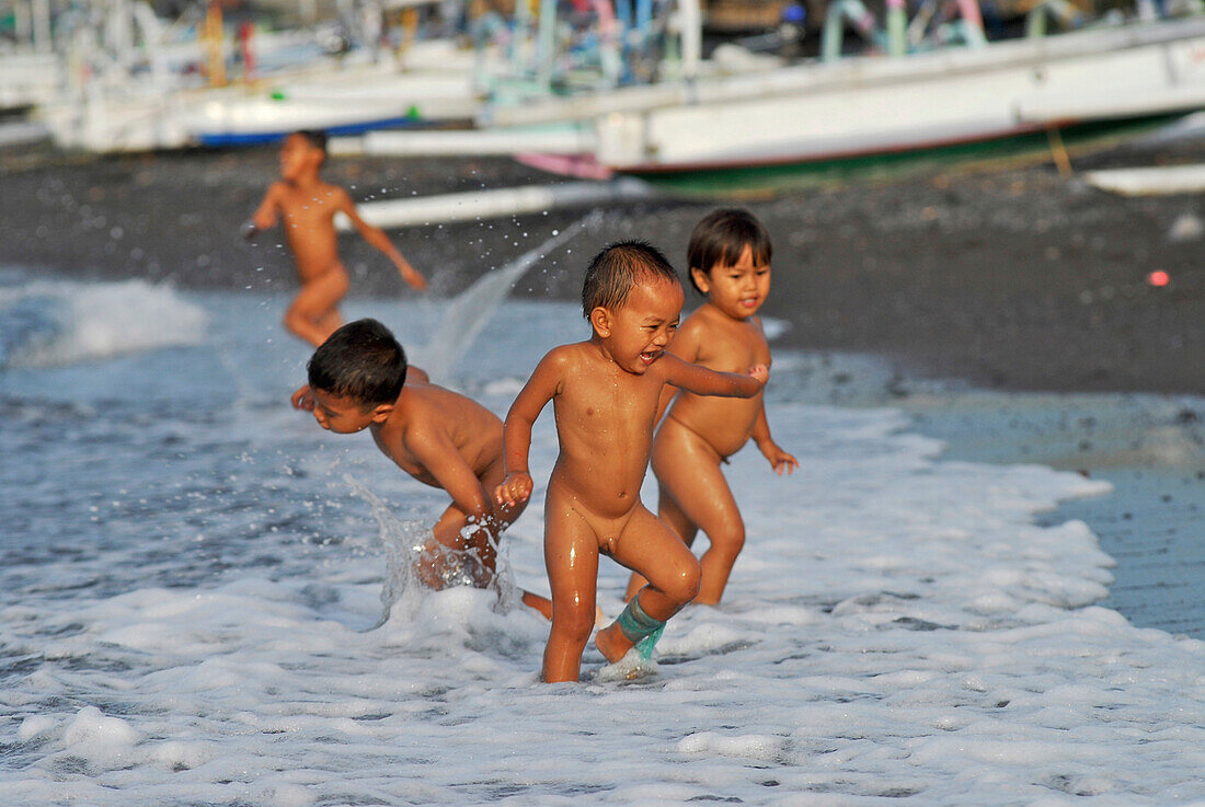 Kinder spielen am Strand im Wasser, Ost Bali, Indonesien, Asien