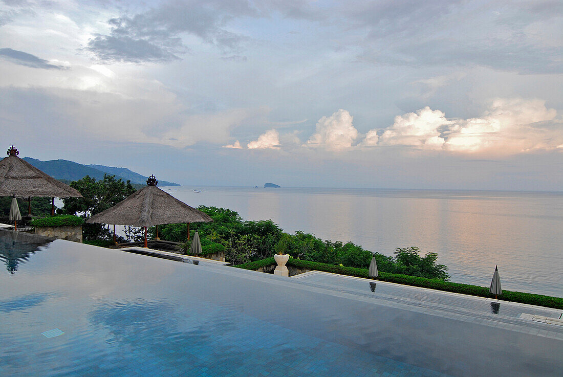The deserted infinity pool at the Amankila Resort under clouded sky, Candi Dasa, Eastern Bali, Indonesia, Asia