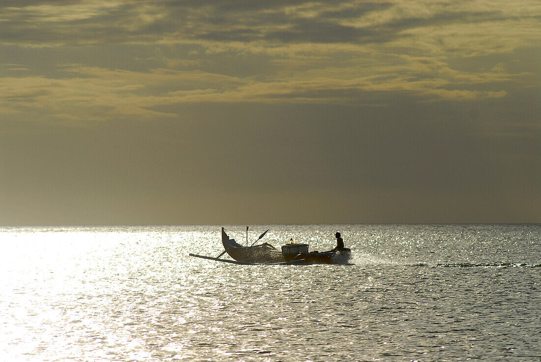 Ein Mann fährt mit seinem Boot aufs Meer, Jimbaran, Bali, Indonesien, Asien