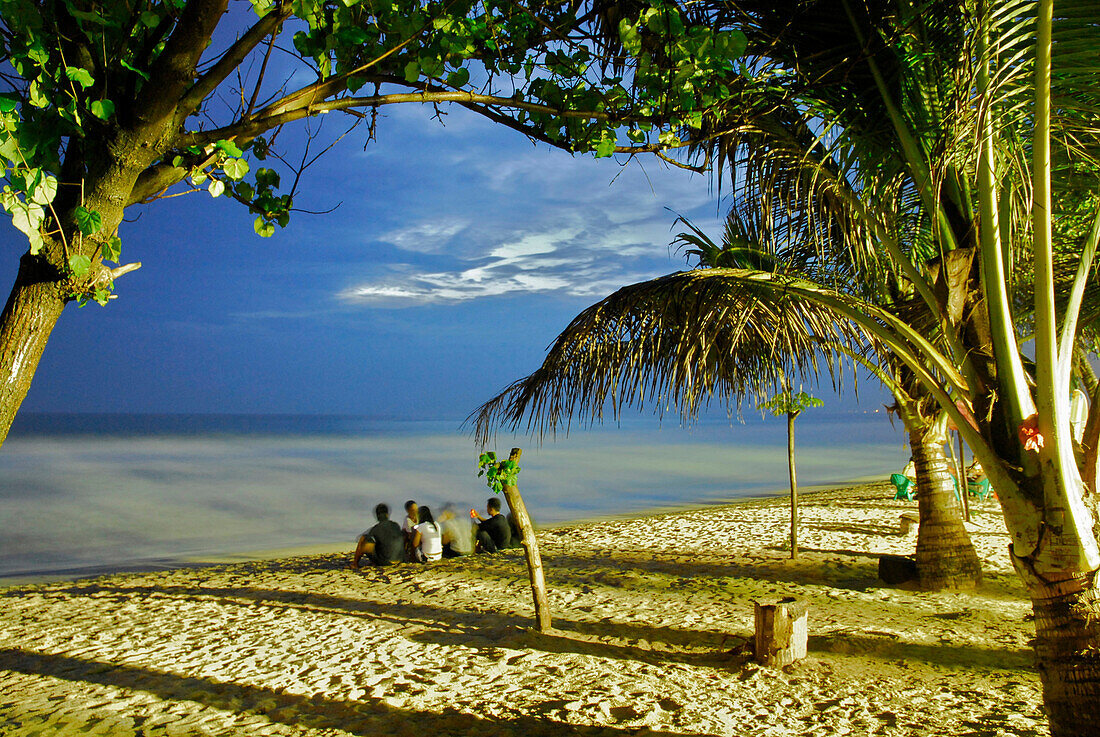 Menschen sitzen am abendlichen Strand von Kuta, Bali, Indonesien, Asien