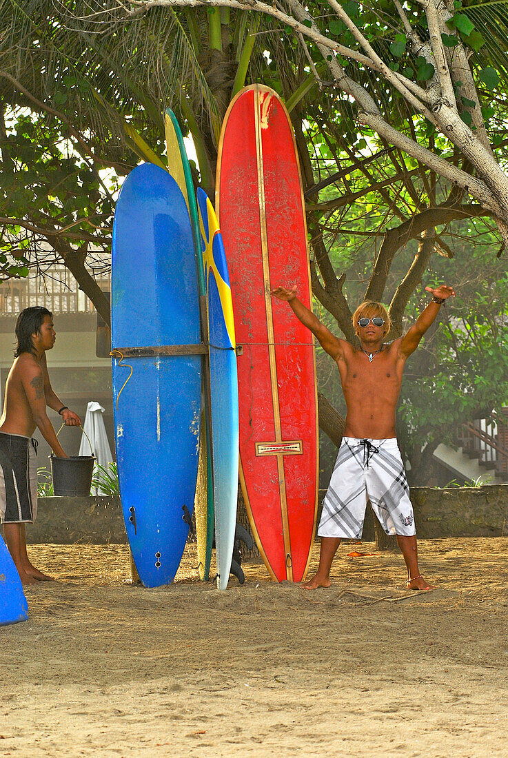 Zwei junge Männer mit Surfbrettern am Strand von Kuta, Bali Indonesien, Asien