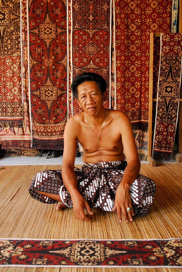 A man and fabric in a shop at Tenganan, Bali Aga village, East Bali, Indonesia, Asia
