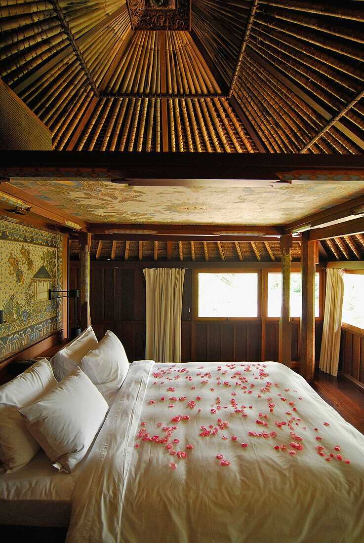 Bett mit Blütenblättern in einem Bungalow des Amandari Resort, Yeh Agung Tal, Bali, Indonesien, Asien