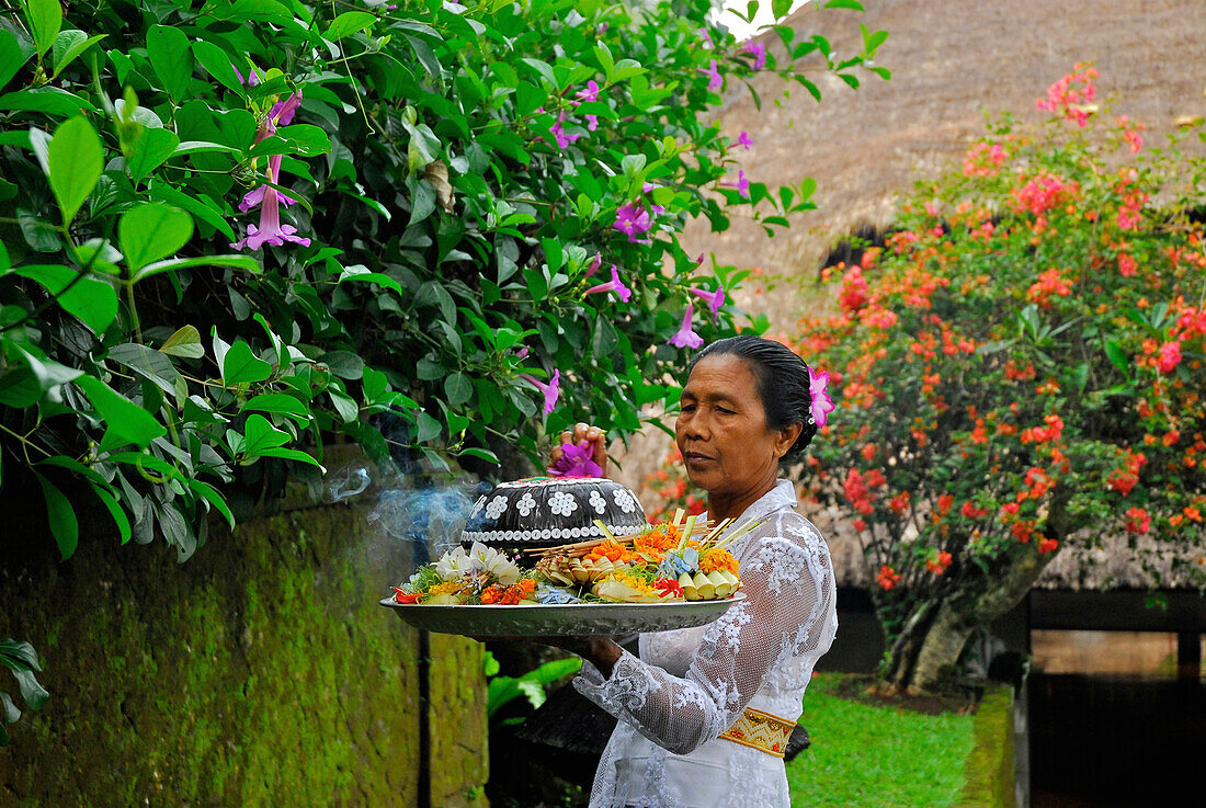 Mature woman with oblation in the garden of the Amandari Hotel, Yeh Agung, Bali, Indonesia, Asia
