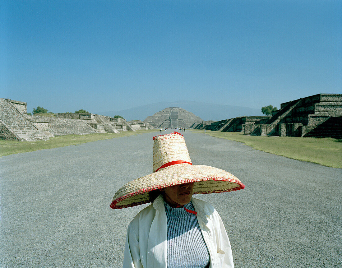 Woman wearing a sombrero standing on the road in front of the moon palace, temple complex Teotihuacan, Mexico, America