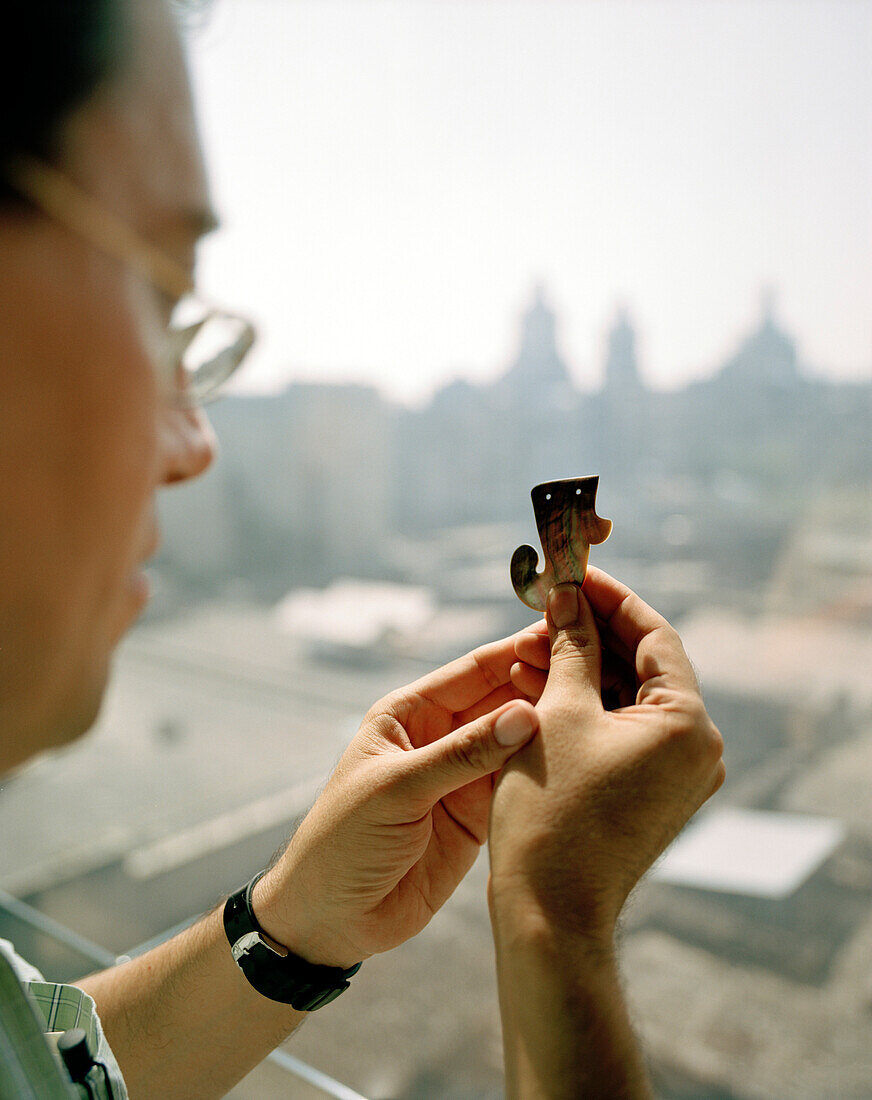 Archaeologist A. Velasquez Castro looking at Aztec hook made of mother of pearl, Archeological Museum at Templo Mayor, Mexico City, Mexico, America