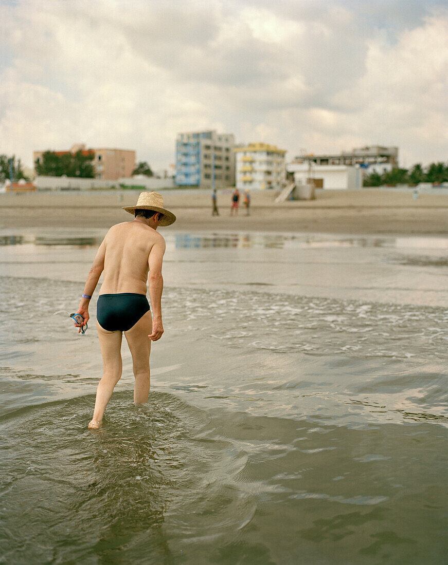Ein Mann mit Hut geht aus dem Wasser, Playa Boca del Rio, Veracruz, Provinz Veracruz, Mexico, Amerika