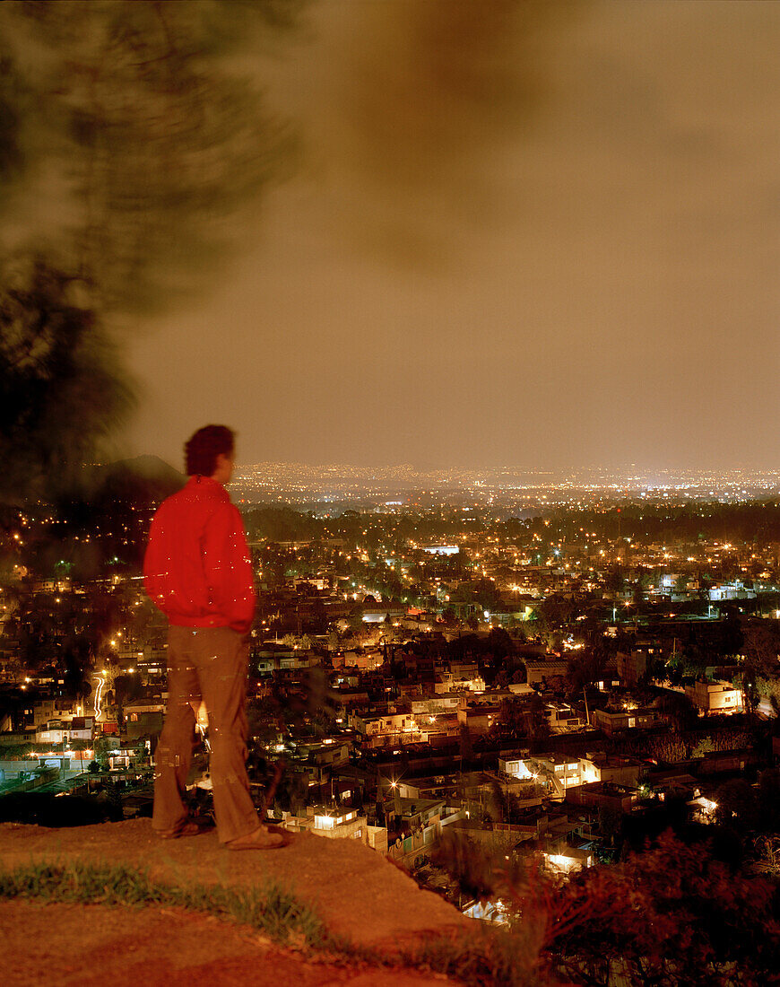 Ein Mann schaut vom Barrio Xochimilco auf die Lichter von Mexico City, Mexiko, Amerika