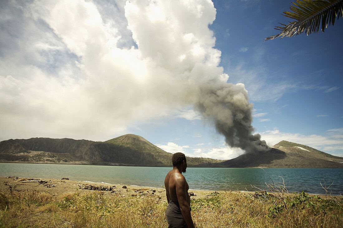 Local villager watching Tavuvur volcano in the distance, from Matupit island, Rabaul East New Britain, PNG
