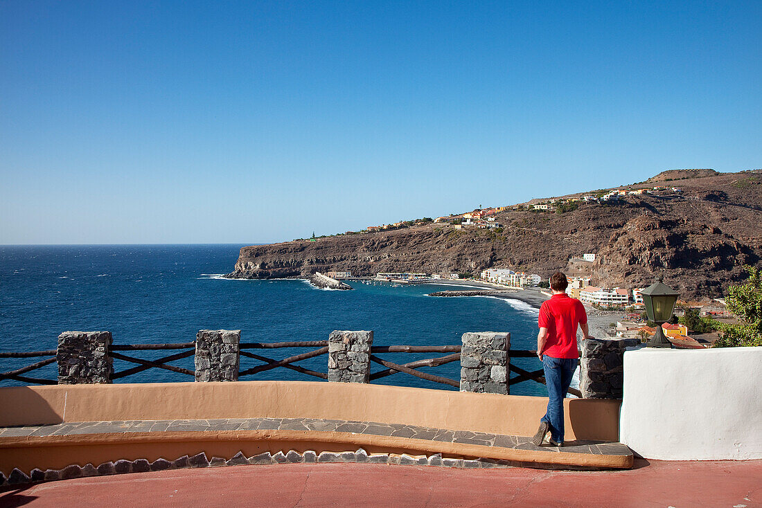 Ein Mann schaut von der Terrasse des Hotel Jardin Tecina auf die Küste, Playa Santiago, La Gomera, Kanarische Inseln, Spanien, Europa