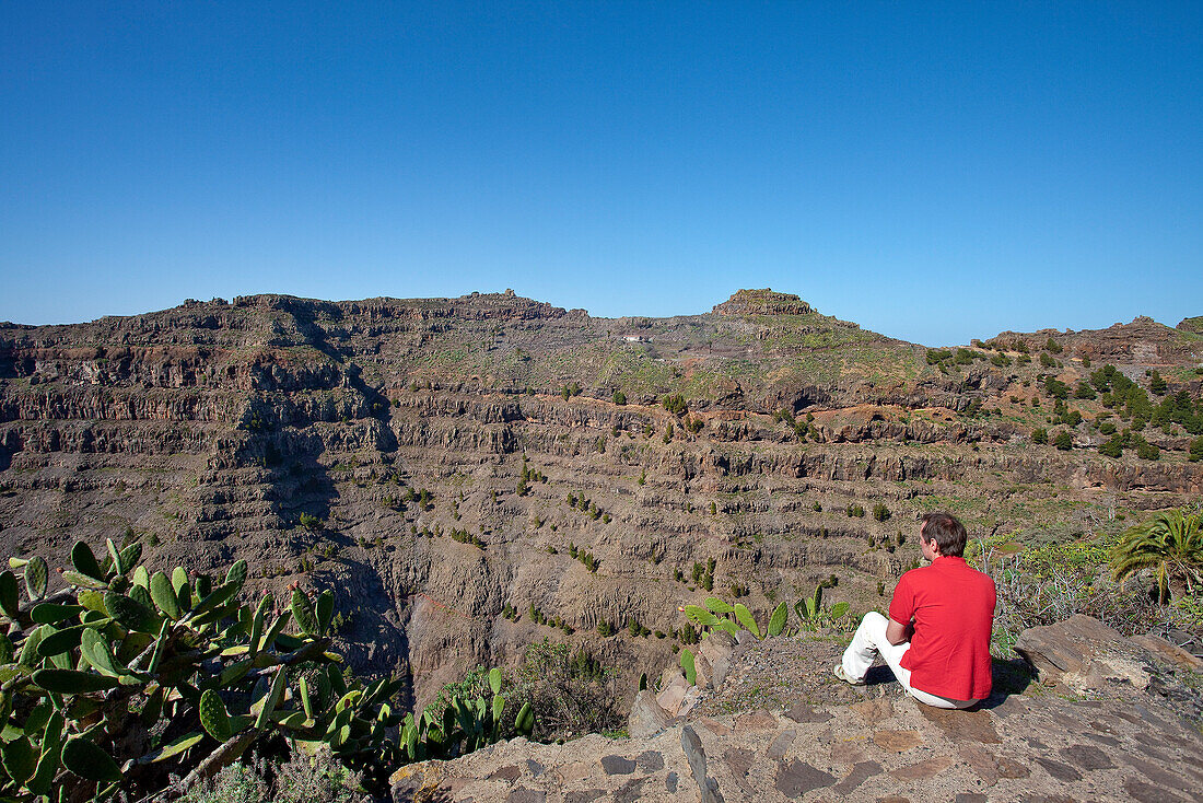 Hiker under blue sky looking at the view, Valle Gran Rey, La Gomera, Canary Islands, Spain, Europe