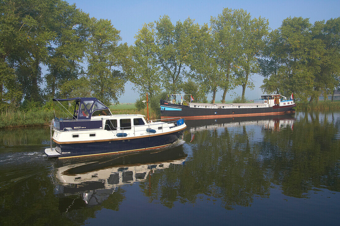 A freighter and a houseboat on the river Vecht, Netherlands, Europe