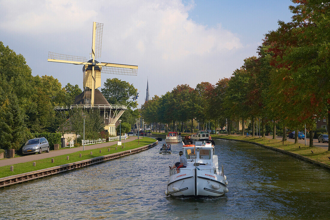 Ein Hausboot fährt auf dem Fluss Smal Weesp an einer Windmühle vorbei, Weesp, Holland, Europa