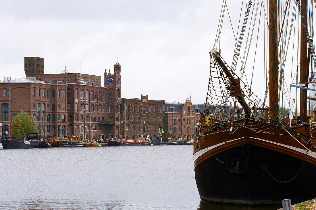 A sailing ship on the river Zaan in front of brick-lined buildings, Wormerveer, Netherlands, Europe