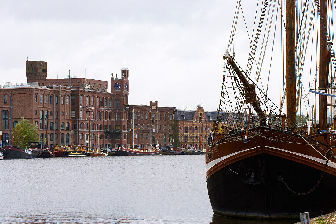 Ein Segelschiff auf dem Fluß Zaan vor Backsteingebäuden, Wormerveer, Holland, Europa