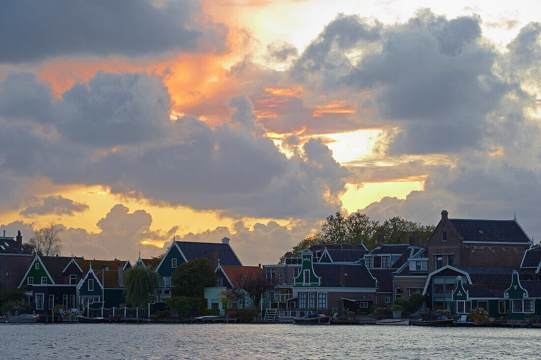 Historische Wohnhäuser am Fluss Zaan unter Wolkenhimmel bei Sonnenuntergang, Zaandijk, Holland, Europa
