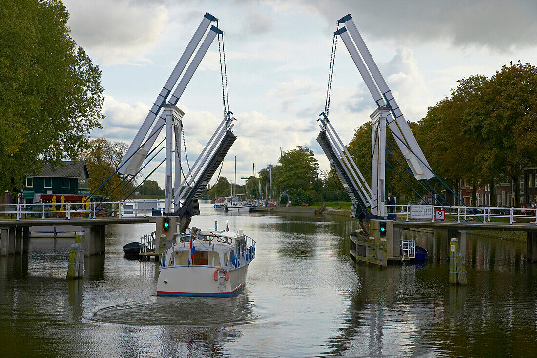 A motorboat on the river Vecht driving past a bascule bridge, Netherlands, Europe