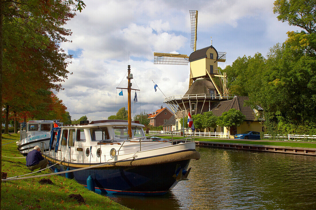 Windmill and houseboat at teh banks of the river Smal Weesp under cloudy sky, Weesp, Netherlands, Europe