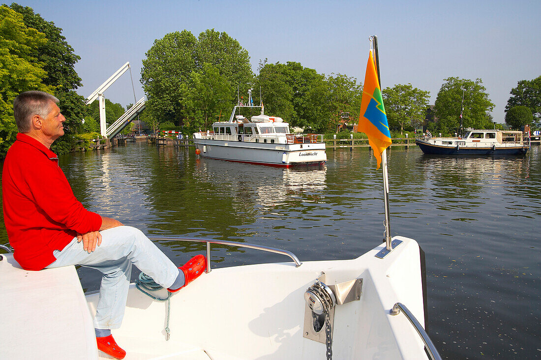 Ein Mann sitzt im Bug eines Bootes, Boote auf dem Fluss Vecht, Niederlande, Europa