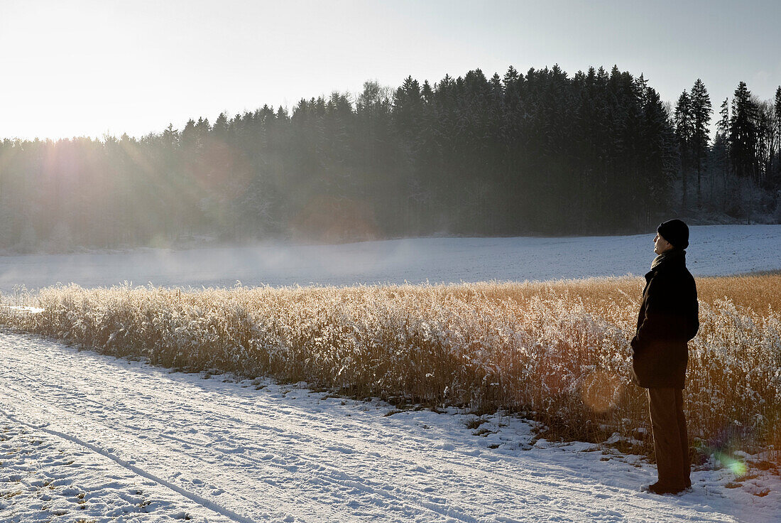 Alter Mann betrachtet Winterlandschaft, Windach, Oberbayern, Deutschland