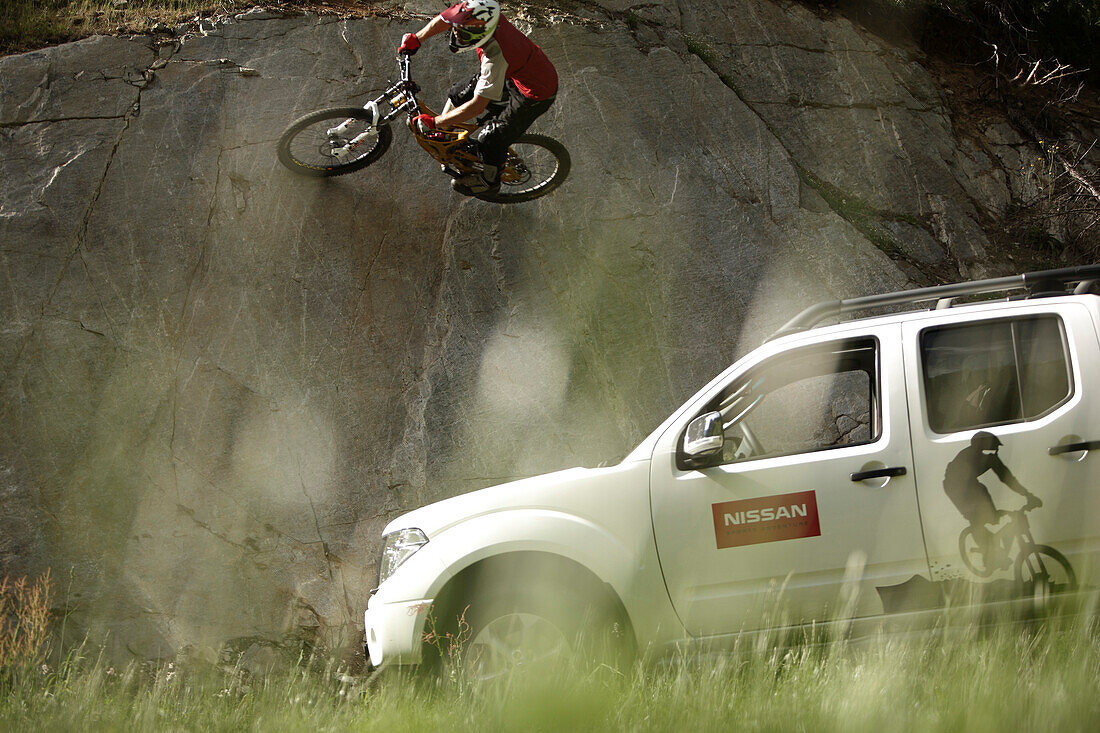 Mountainbiker fährt an einer steilen Felswand, Ischgl, Tirol, Österreich