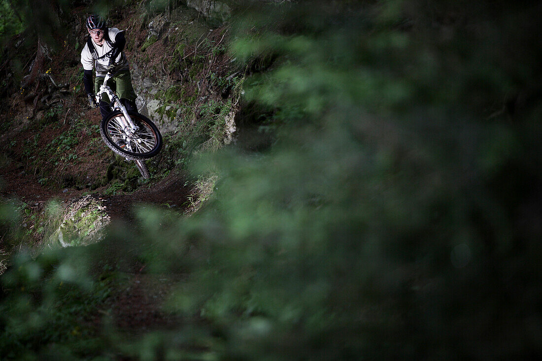 Mountainbiker jumping in the forest, Ischgl, Tyrol, Austria