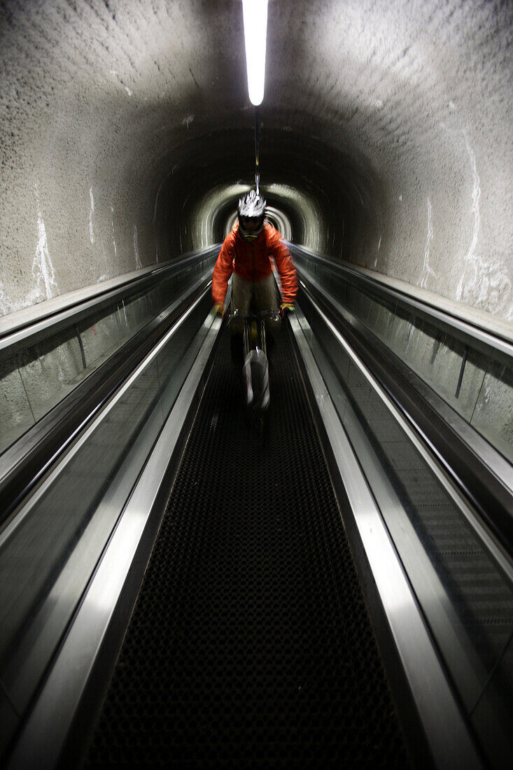 Mountainbiker riding down an escalator, Ischgl, Tyrol, Austria